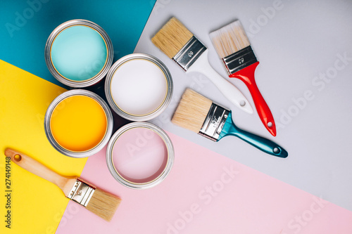 Fototapeta Naklejka Na Ścianę i Meble -  Four open cans of paint with brushes on bright background.
