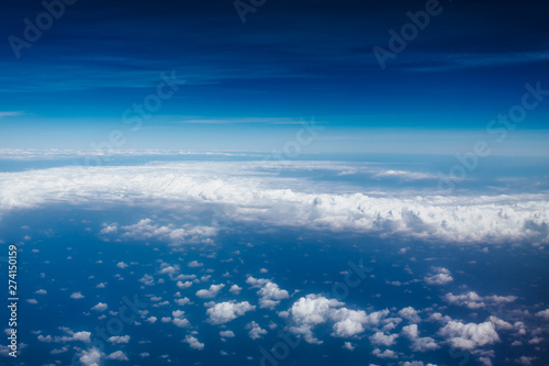 Plane window view with blue sky and beautiful clouds. As seen through window of an aircraft. View of wing & ocean. Airplane from city Bangkok to island Bali.