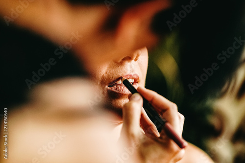 Make-up artist retouches the color of a client's lips.