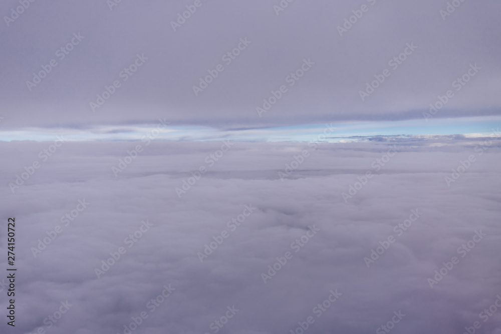 Plane window view with blue sky and clouds. Clouds and sky as seen through window of an aircraft. View of beautiful cloud, ocean and city from the airplane.