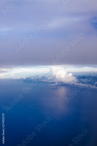 Plane window view with blue sky and clouds. Clouds and sky as seen through window of an aircraft. View of beautiful cloud, ocean and city from the airplane.