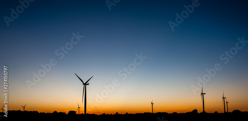 Multiple wind turbine outlines on orange and blue sky. © ArchonCodex