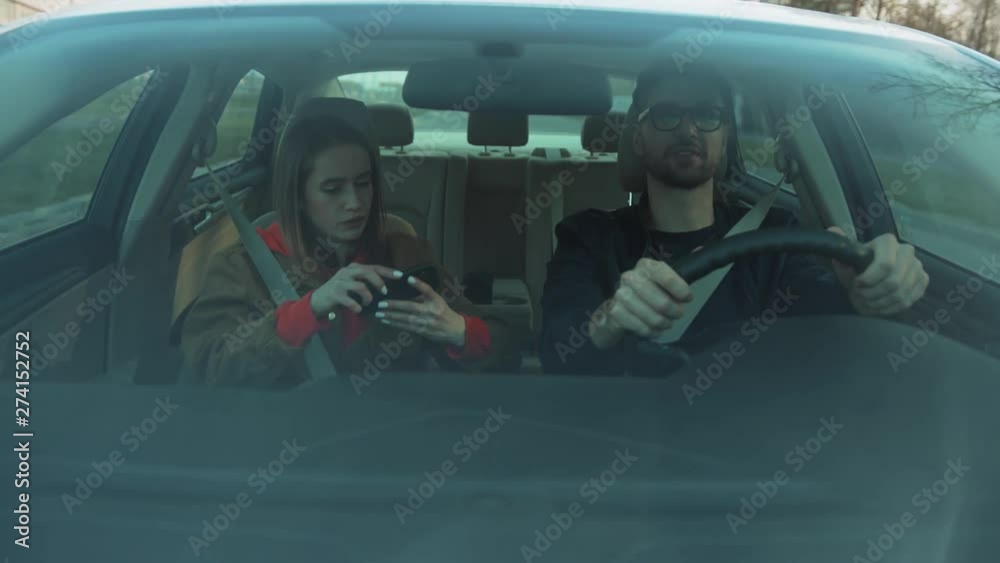 Young driver pointing finger at building. Girlfriend using navigator app on smartphone. Serious girl showing way. Automobile concept, cellphone, innovation, message, communication, holding, automobile