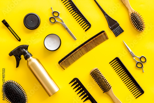 Combs, spray, sciccors and hairdresser tools in beauty salon work desk on yellow background top view pattern photo