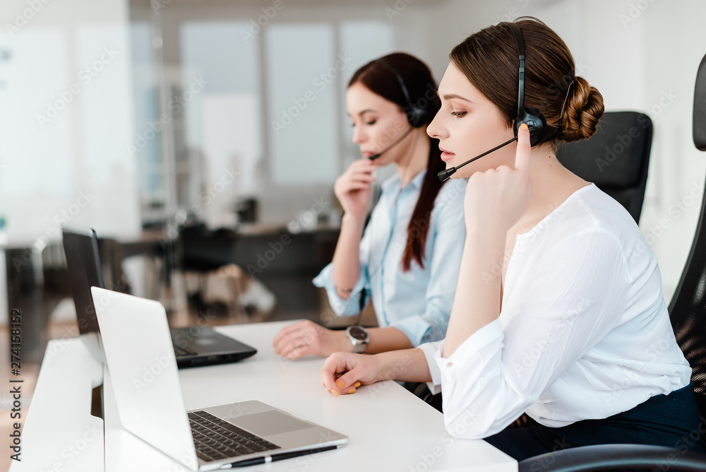 Serious young office worker with a headset answering in a call center, woman talking with clients. Portrait of an attractive customer and technical support representative. Business concept Serious young office worker with a headset answering in a call center, woman talking with clients. Portrait of an attractive customer and technical support representative. Business concept