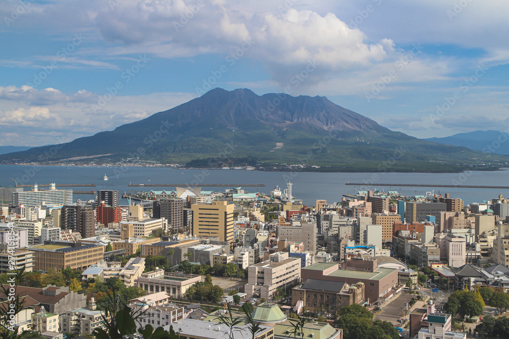 Cityscape with Sakurajima mountain, sea and blue sky background view from Shiroyama Park Observation park, Kagoshima, Kyushu, Japan