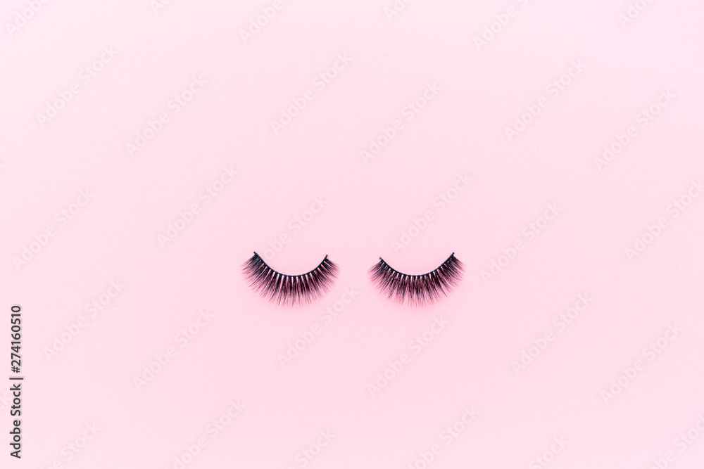 False eyelashes lying on pink background. Beauty and makeup concept. Flatlay, mockup, overhead, top view copy space False eyelashes lying on pink background. Beauty and makeup concept. Flatlay, mockup, overhead, top view copy space