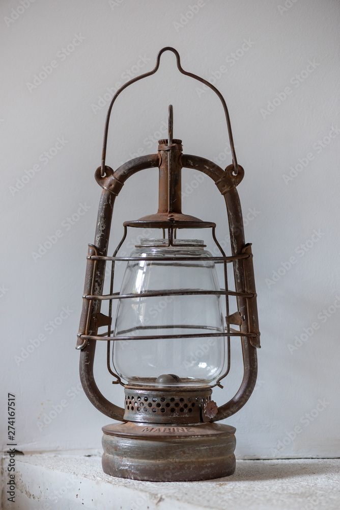Old oil lamp close-up view against white wall Old oil lamp close-up view against white wall