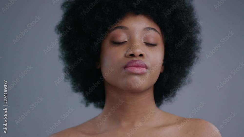 Portrait of pretty afro-american black woman sprinkling micellar water on face after make-up in a salon. Close-up of charming lady caring for face skin looking at camera. Portrait of pretty afro-american black woman sprinkling micellar water on face after make-up in a salon. Close-up of charming lady caring for face skin looking at camera.