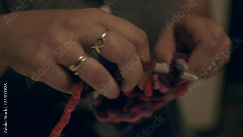 A closeup to a woman's hands doing Pink and purple wool crafts knitting with stitches. photo