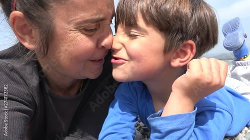 4K Selfie Mother and son pull and rub their faces resting on the beach photo