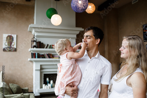 Tender family hugs. Happy pregnant mom, dad, daughter enjoy each other at home