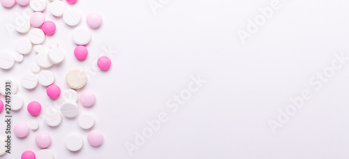Pink and white pills on white background. Heap of assorted various medicine tablets and pills. Health care. Copy space. Top view. Horizontal banner
