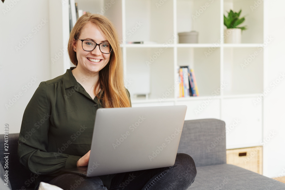 freundliche junge frau mit laptop im wohnzimmer freundliche junge frau mit laptop im wohnzimmer