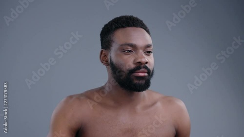 Naked attractive smiling young black man swiping on virtual screen future technology standing on grey background. Potrait of handsome african man model. photo