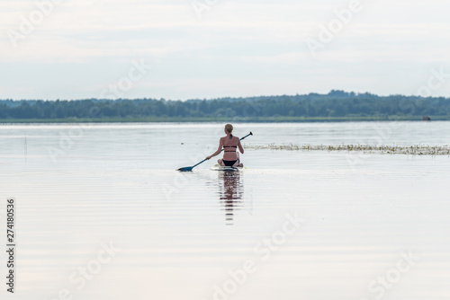 Female Paddler Sitting on a Stand Up Paddle Board on a Still Lake