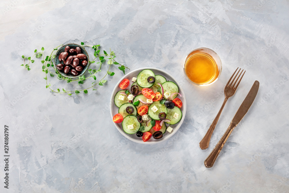 Greek salad. An overhead photo of a plate of fresh salad of feta cheese, cherry tomatoes, cucumbers, onions and olives. A dinner with white wine Greek salad. An overhead photo of a plate of fresh salad of feta cheese, cherry tomatoes, cucumbers, onions and olives. A dinner with white wine