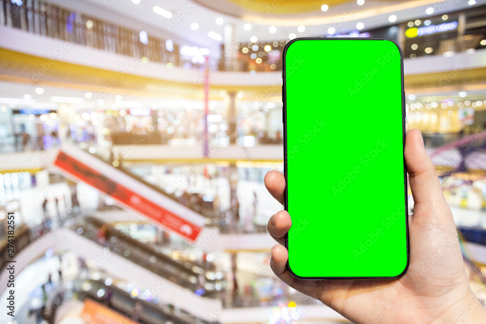 Close-up of female use Hand holding smartphone blurred images touch of Abstract blur of inside shopping complex background,shopping online concept. Close-up of female use Hand holding smartphone blurred images touch of Abstract blur of inside shopping complex background,shopping online concept.