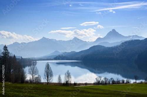 weissensee lake in morning light in front of the mountains of the bavarian alps against a blue sky near fuessen, allgaeu, southern germany, copy space photo