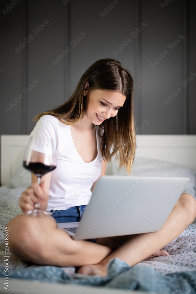 Happy woman using a laptop searching online on the bed at home Happy woman using a laptop searching online on the bed at home