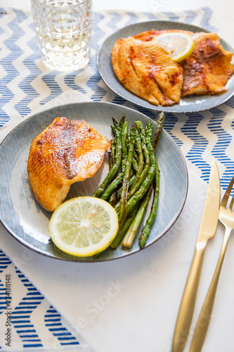 Baked tilapia fish with asparagus on a ceramic plate. Healthy mediterranean diet lunch or dinner.