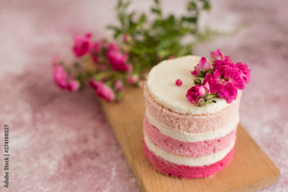 Beautiful pink cream and berries cake on a light concrete background. Birthday celebration