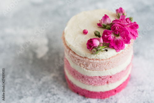 Beautiful pink cream and berries cake on a light concrete background. Birthday celebration