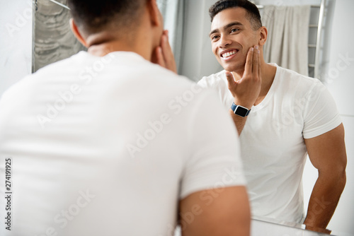 Happy young man touching his shaving face