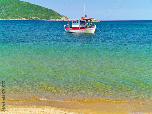 Beautiful sandy beach with crystal clear water and boat in Nea Peramos, Greece. photo