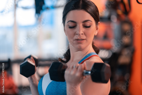 Mature woman feeling excited while holding barbells in arms