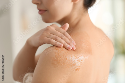 Fotografía Beautiful young woman applying body scrub at home, closeup