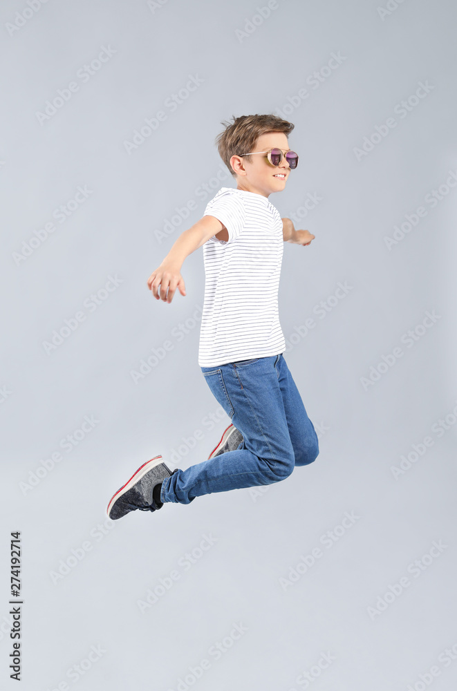 Jumping boy in jeans on grey background