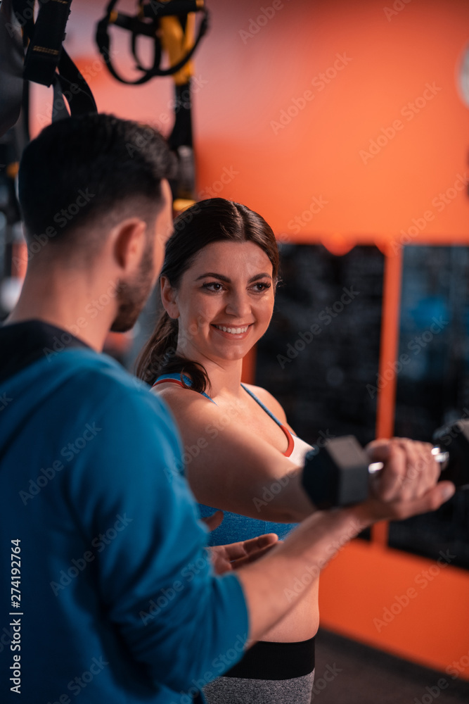 Woman smiling while talking to trainer and doing exercises Woman smiling while talking to trainer and doing exercises