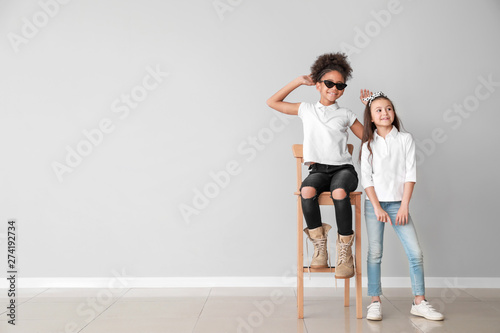 Stylish girls in jeans near grey wall