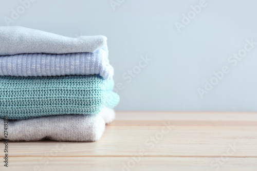 Stack of warm clothes on table against light background