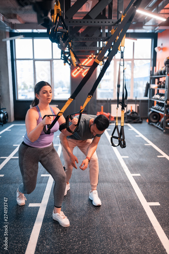 Overweight woman wearing sport clothing exercising on TRX