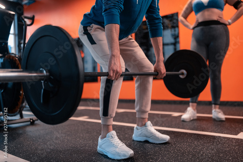 Man wearing white sneakers working out with barbell