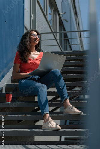 Charming young woman with notebook on her laps sitting on stairs © Yakobchuk Olena
