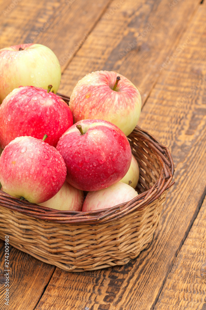 Red apples in wicker basket on wooden boards Red apples in wicker basket on wooden boards