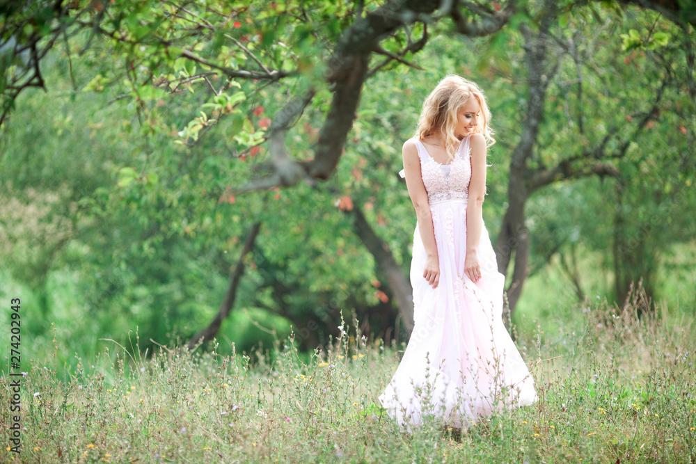 beautiful young woman in a gentle pink dress on nature