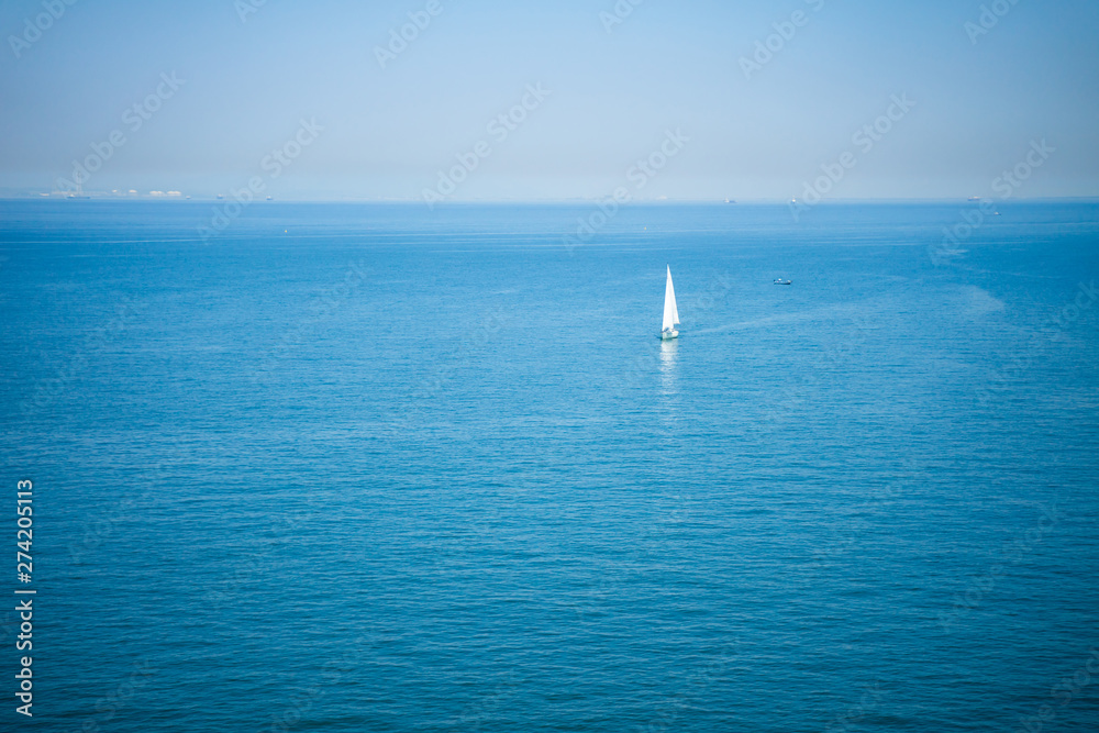 Fototapeta premium The sailboat is sailing in the clear blue sea on a clear day.