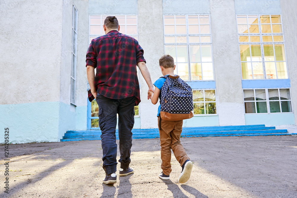 Back to school. Happy father and son go to elementary school. Back to school. Happy father and son go to elementary school.