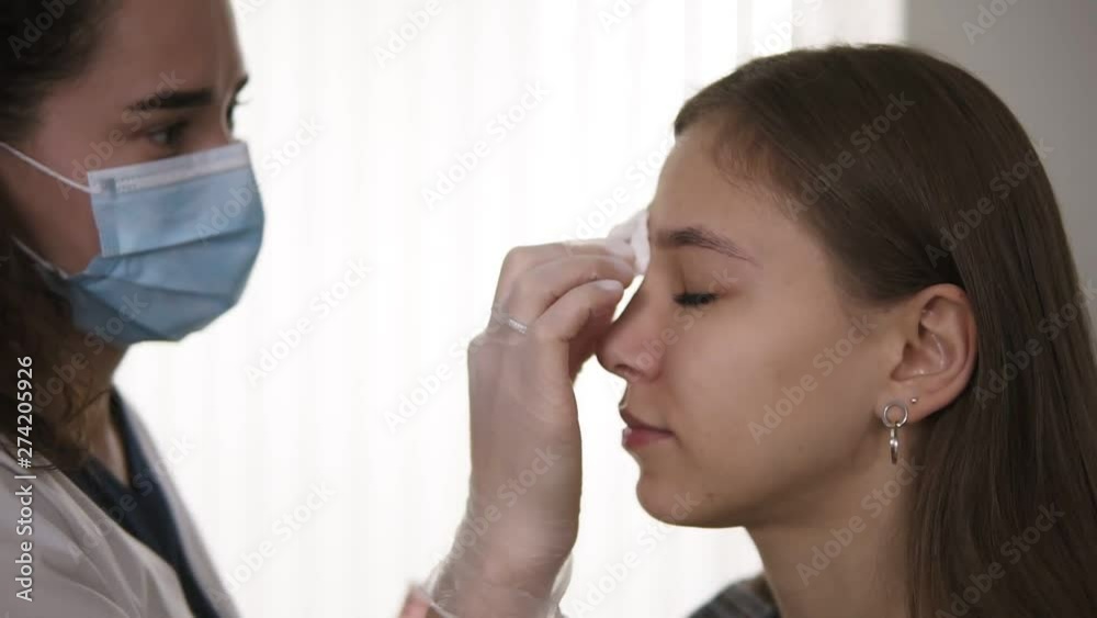 Eyebrow correction. Beautician rubs client's eyebrows with a cotton pad, disinfection. Side view Eyebrow correction. Beautician rubs client's eyebrows with a cotton pad, disinfection. Side view