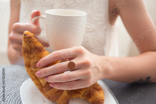 A cup of tea or coffee in the hands of a young woman. Business breakfast
