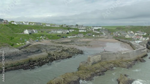 An aerial view of Collieston village from the sea on a cloudy day. Flying in towards the beach and village through the harbour entrance. photo