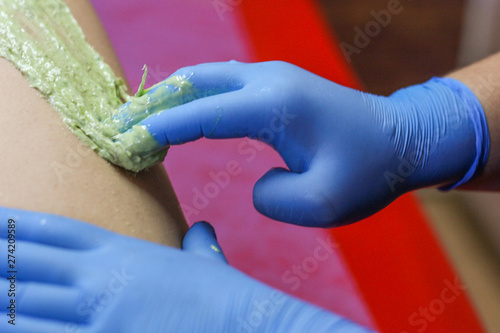 Girl cosmetician in medical gloves with pasta for shugaring photo