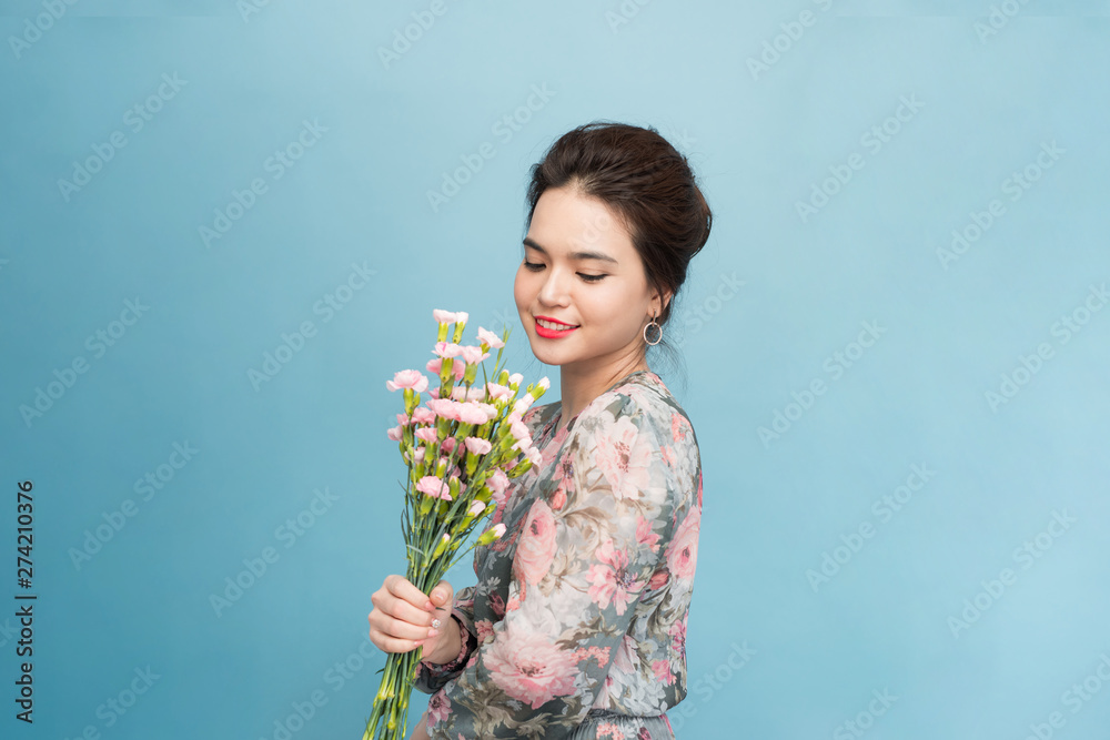 Young beautiful Aisa girl holding a bouquet on blue background Young beautiful Aisa girl holding a bouquet on blue background