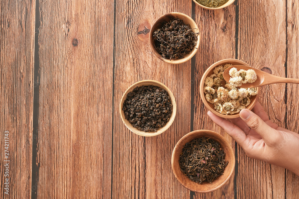assortment of dry tea in white bowls on wooden surface assortment of dry tea in white bowls on wooden surface