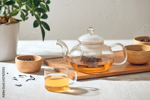 Tea in a transparent cup and teapot on a wooden background photo