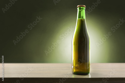 Beer bottle filled and closed on wood table green background.